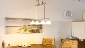 A dining area with a wooden table, four chairs, a hanging light fixture, and a wall-mounted clock. - liebevoll eingerichtetes Appartement (Rechlin)