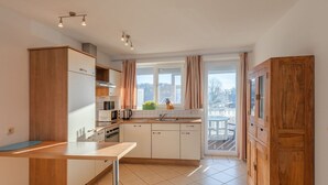 A modern kitchen with wooden cabinets, a built-in oven, and a large window with curtains.