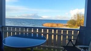 A balcony with a view of the sea and a grassy area.