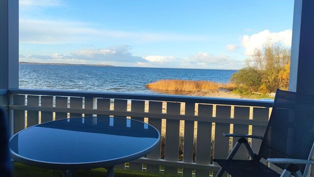 Un balcon avec vue sur la mer et un espace verdoyant.