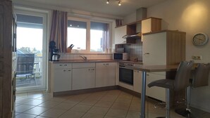 Une cuisine moderne avec des meubles blancs, un four à micro-ondes et un évier. On y trouve également un coin repas avec deux chaises et une table.