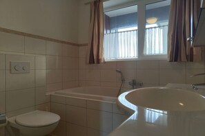 A bathroom with a toilet, bathtub, and sink.
