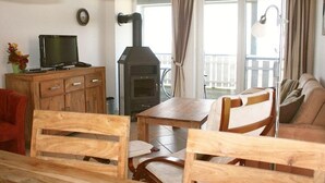 A living room with a TV, wooden furniture, a fireplace, and a balcony with curtains. - liebevoll eingerichtetes Appartement (Rechlin)