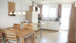 A modern kitchen with white cabinets, a wooden dining table, and a coffee machine. - liebevoll eingerichtetes Appartement (Rechlin)