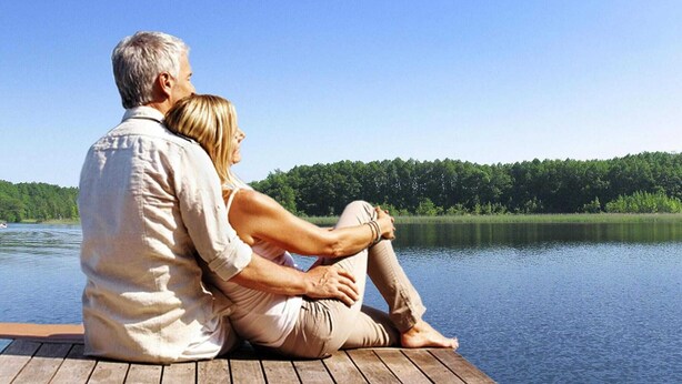 A couple sitting on a wooden dock overlooking a calm lake with a forested shoreline. - Ferienhaus im skandinavischen Stil (Granzow)