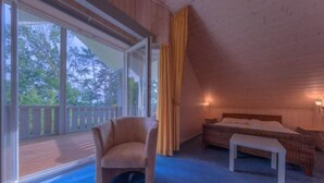 A bedroom with a large window, a chair, a bed, and a small table. - Ferienhaus im skandinavischen Stil (Granzow)