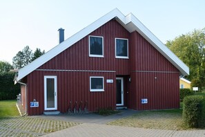 A red building with a white roof, a door, and a window. There is a sign with the number 250.