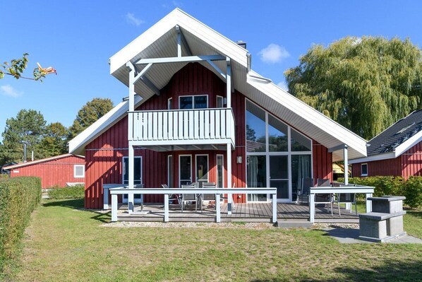 A red building with a white balcony and a deck.