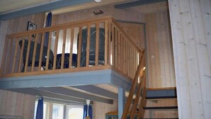 A wooden interior with a balcony, a staircase, and a window with curtains. - skandinavisches Ferienhaus in Mirow (Granzow)