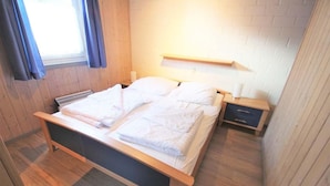 A single bed with a wooden frame and white bedding in a room with wooden walls and floors. - exklusives skandinavisches Ferienhaus (Granzow)