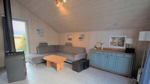 A cozy room with a sofa, a wooden table, a cabinet, and a fireplace. - exklusives skandinavisches Ferienhaus (Granzow)