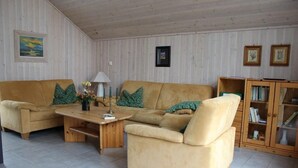 A cozy living room with a beige sofa, a wooden coffee table, and a bookshelf. - skandinavisches Ferienhaus in Mirow (Granzow)