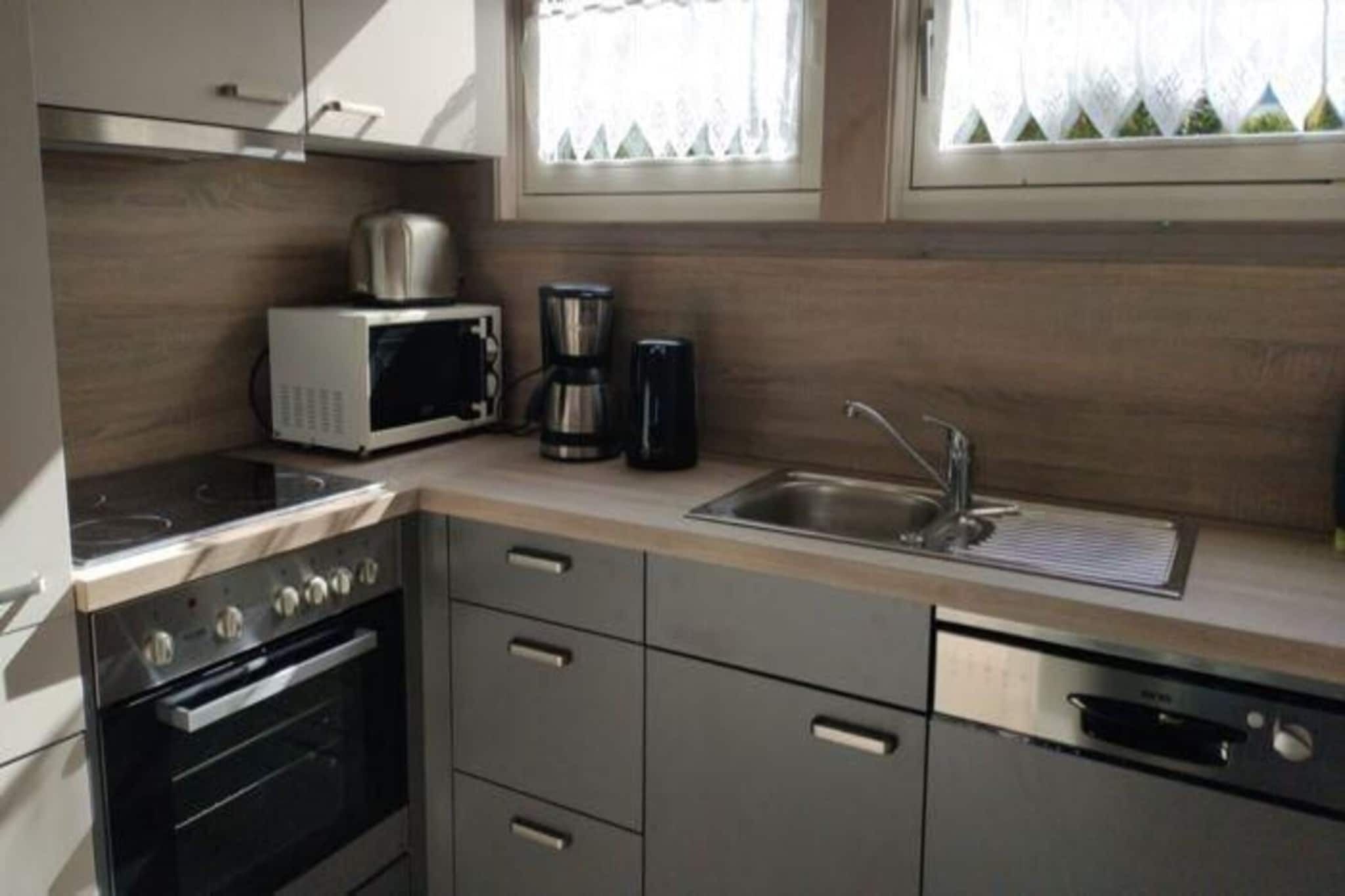 Una cocina moderna con electrodomésticos de acero inoxidable, microondas, cafetera y lavavajillas.