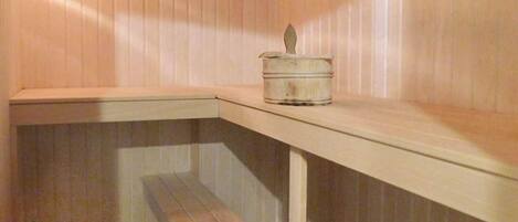 A corner of a room with a wooden bench and a small white container on a shelf.