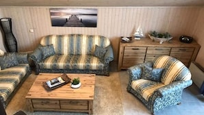 Ein gemütliches Wohnzimmer mit gestreiften Sofas, einem Holztisch und Blick auf einen Steg.