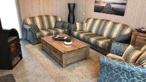 Ein Wohnzimmer mit gestreiften Sofas, einem Holztisch und einem Kamin.