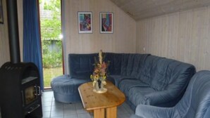 A living room with a sofa, a wooden table with a vase, and a fireplace. - Ferienhaus im Ferienpark Mirow (Granzow)
