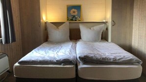 A double bed with white linens, a painting of sunflowers on the wall, and a wooden headboard. - Ferienhaus im skandinavischen Stil (Granzow)