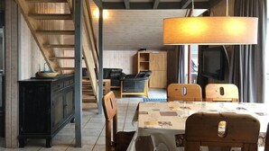 A cozy interior with a staircase, wooden furniture, a dining table, and a television. - Ferienhaus im skandinavischen Stil (Granzow)