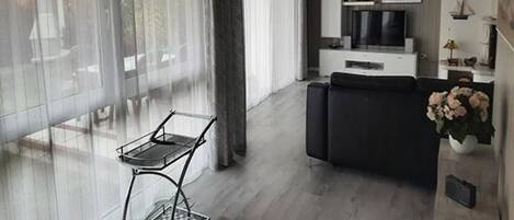 Una sala de estar moderna con un sofá, un televisor y un comedor con una mesa y sillas.