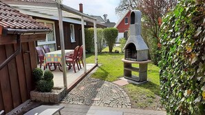 Un patio con una chimenea de piedra, una zona de estar cubierta con sillas y un horno de piedra.