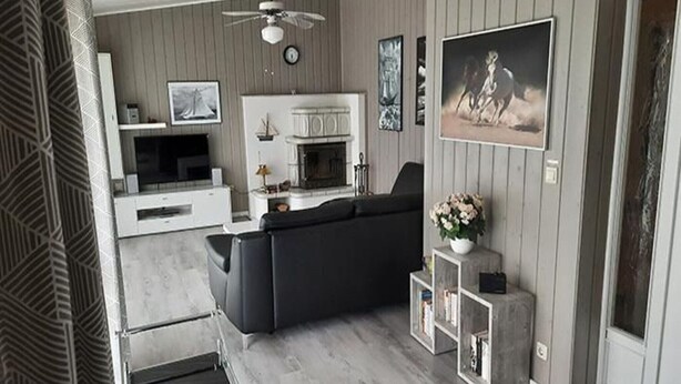 Una sala de estar moderna con chimenea, sofá negro y televisor.