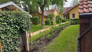 Un barrio residencial con valla de madera, césped cuidado y casas con tejados marrones.
