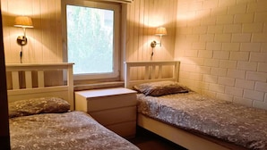 Een slaapkamer met twee eenpersoonsbedden, een raam en twee wandlampen.