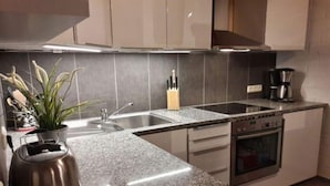 Een moderne keuken met een granieten aanrecht, roestvrijstalen apparatuur en een ingebouwde oven.