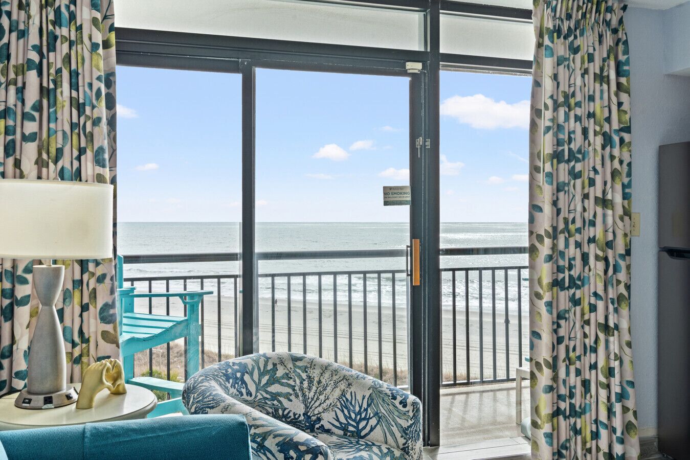 Una habitación con vista a la playa, un sofá, una lámpara y un cartel de 'No Fumar'.