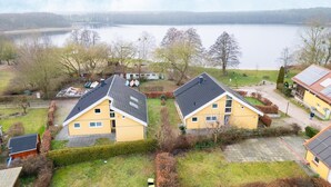 A residential area with two yellow houses, a lake, and a bridge in the background. - Ferienhaus im Ferienpark Mirow (Granzow)