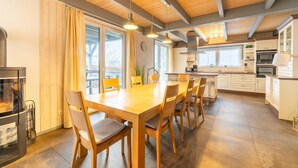 A spacious kitchen with wooden cabinets, a dining table with chairs, and a large window providing natural light.
