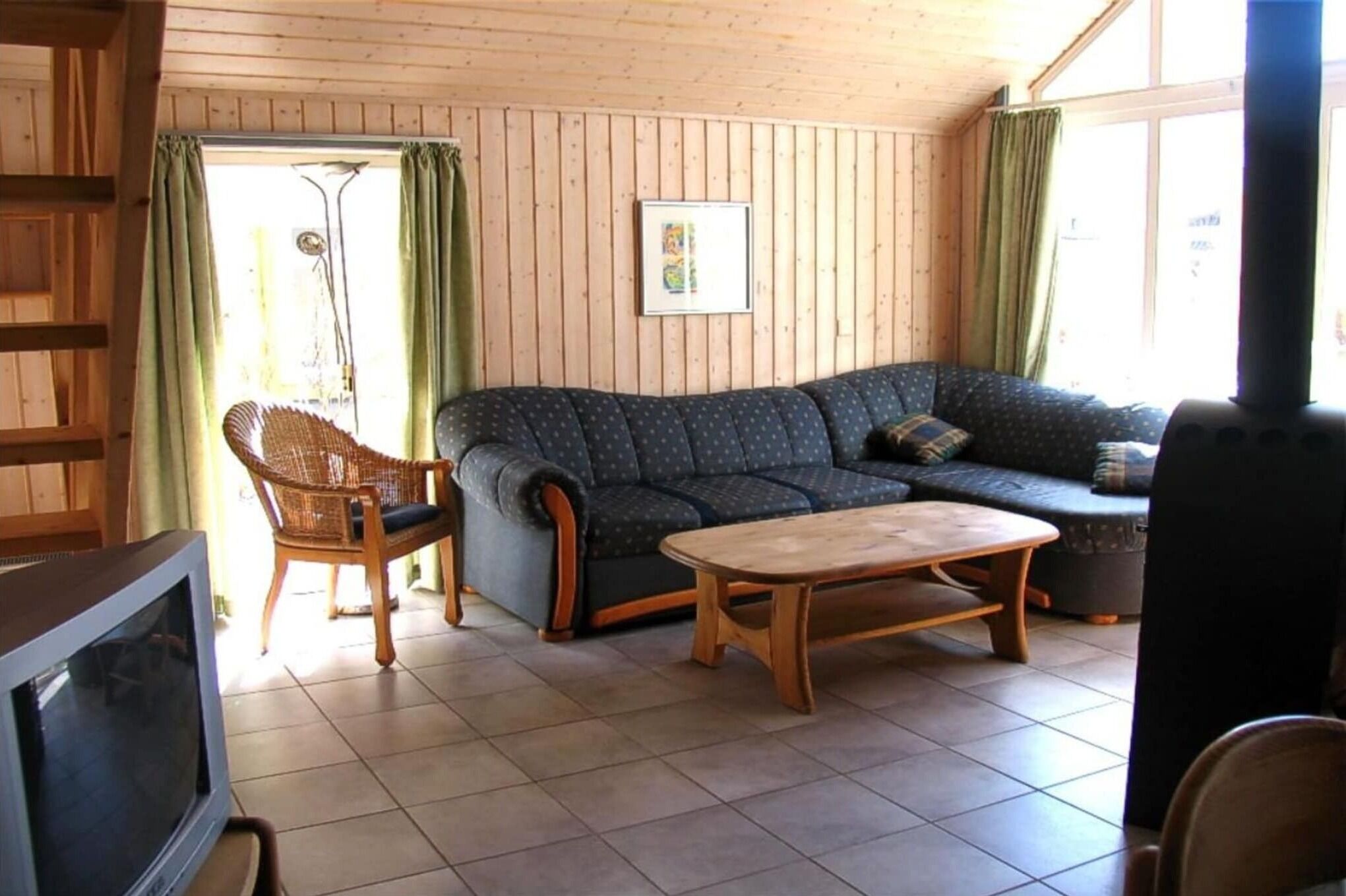 A cozy living room with a sofa, a wooden coffee table, and a wicker chair.