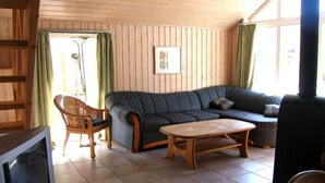 A cozy living room with a sofa, a wooden coffee table, and a wicker chair.