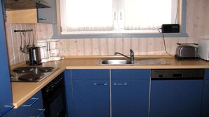 A kitchen with blue cabinets, a stove, a sink, and a window with curtains.