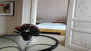 Ett rum med en säng, ett litet bord med en krukväxt och en inramad tavla på väggen.