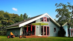 A house with a covered patio, a lawn, and a lawn mower. - skandinavisches Ferienhaus in Mirow (Granzow)
