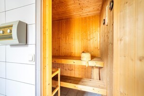 Una sauna con paredes y bancos de madera, un perchero para toallas y un calentador.