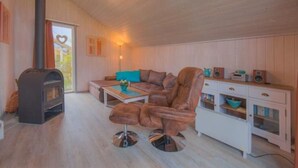A cozy living room with a brown leather sofa, a coffee table, a fireplace, and a white cabinet with drawers. - Ferienhaus im Ferienpark Mirow (Granzow)