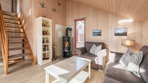 A cozy living room with a wooden interior, a fireplace, a sofa, a coffee table, and a bookshelf.