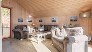 A cozy living room with wooden walls and ceiling, featuring two sofas, a coffee table, and a floor lamp.