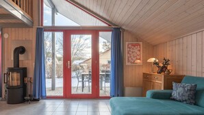 Ein gemütliches Blockhaus mit Holzausstattung, einer Couch, einem Tisch, einem Kamin und einer Glastür zum Außenbereich.