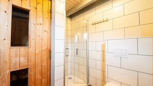 A bathroom with wooden walls, a glass shower enclosure, and a white toilet. - Ferienhaus im skandinavischen Stil (Granzow)