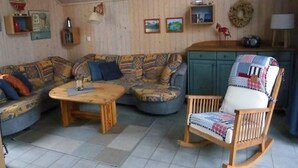 A cozy living room with a patterned sofa, a wooden rocking chair, and a small table. - Ferienhaus im skandinavischen Stil (Granzow)