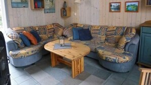 A cozy living room with a blue sofa set, a wooden coffee table, and a lamp. - Ferienhaus im skandinavischen Stil (Granzow)