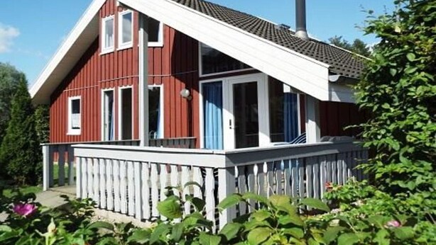 A red wooden house with a white porch and a chimney. - Ferienhaus im skandinavischen Stil (Granzow)