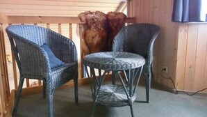 Two wicker chairs with cushions and a small round table in a room with wooden walls and a wooden railing. - Ferienhaus im skandinavischen Stil (Granzow)