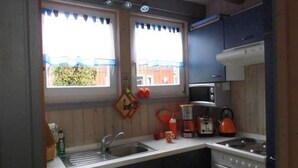 A compact kitchen with a sink, stove, and microwave. - Ferienhaus im skandinavischen Stil (Granzow)