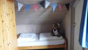 A small, single-bed room with a wooden bunk bed and a teddy bear on the bed. - Ferienhaus im skandinavischen Stil (Granzow)