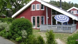 Une maison rouge avec un porche blanc et un parasol bleu.